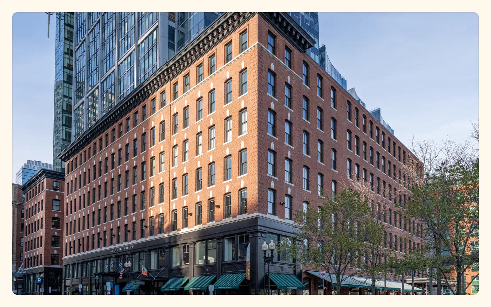 The historic brick facade of Atlantic Wharf rises beneath a modern glass tower on Congress Street in Boston.