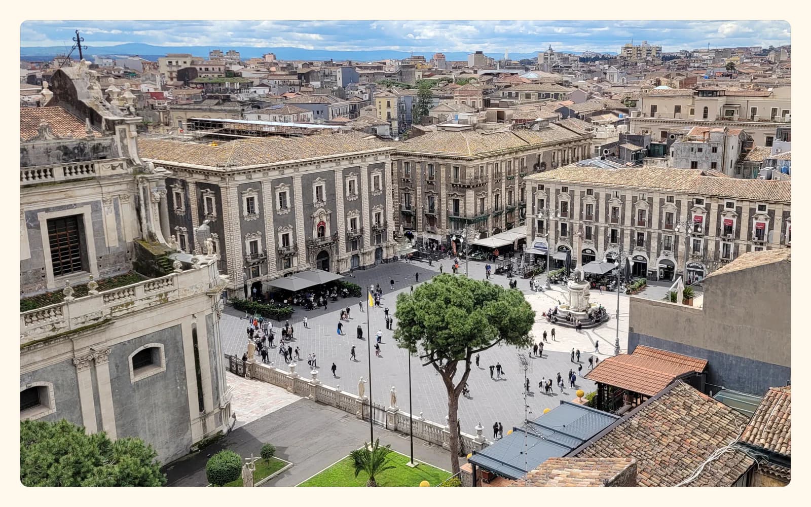 Catania's Piazza del Duomo in warm daylight, with the cathedral and surrounding baroque buildings.