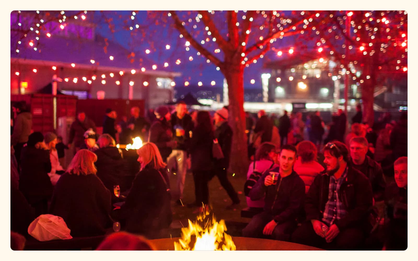 Crowds gather around a fire under red and white string lights at Dark Mofo's Winter Feast in Hobart.