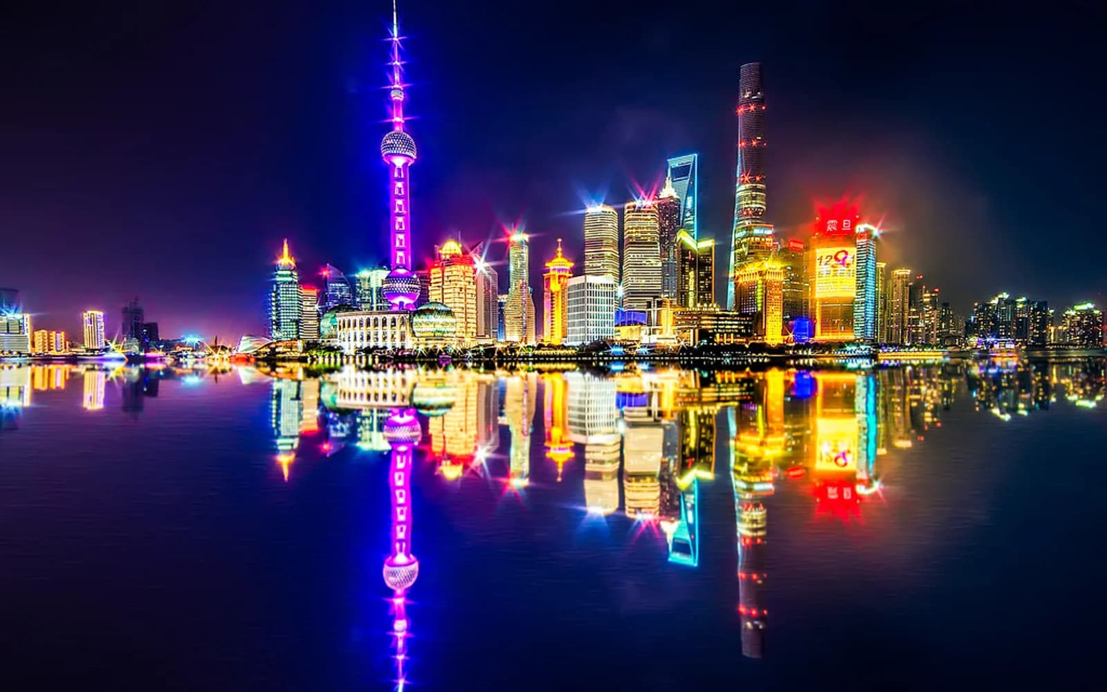 Shanghai's Pudong skyline with Shanghai Tower and other tall buildings under a bright blue sky.